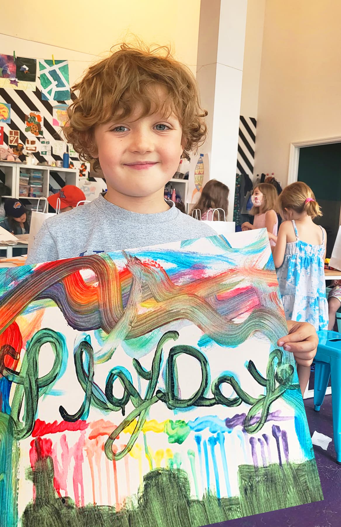 Child holding a Playday rainbow painting